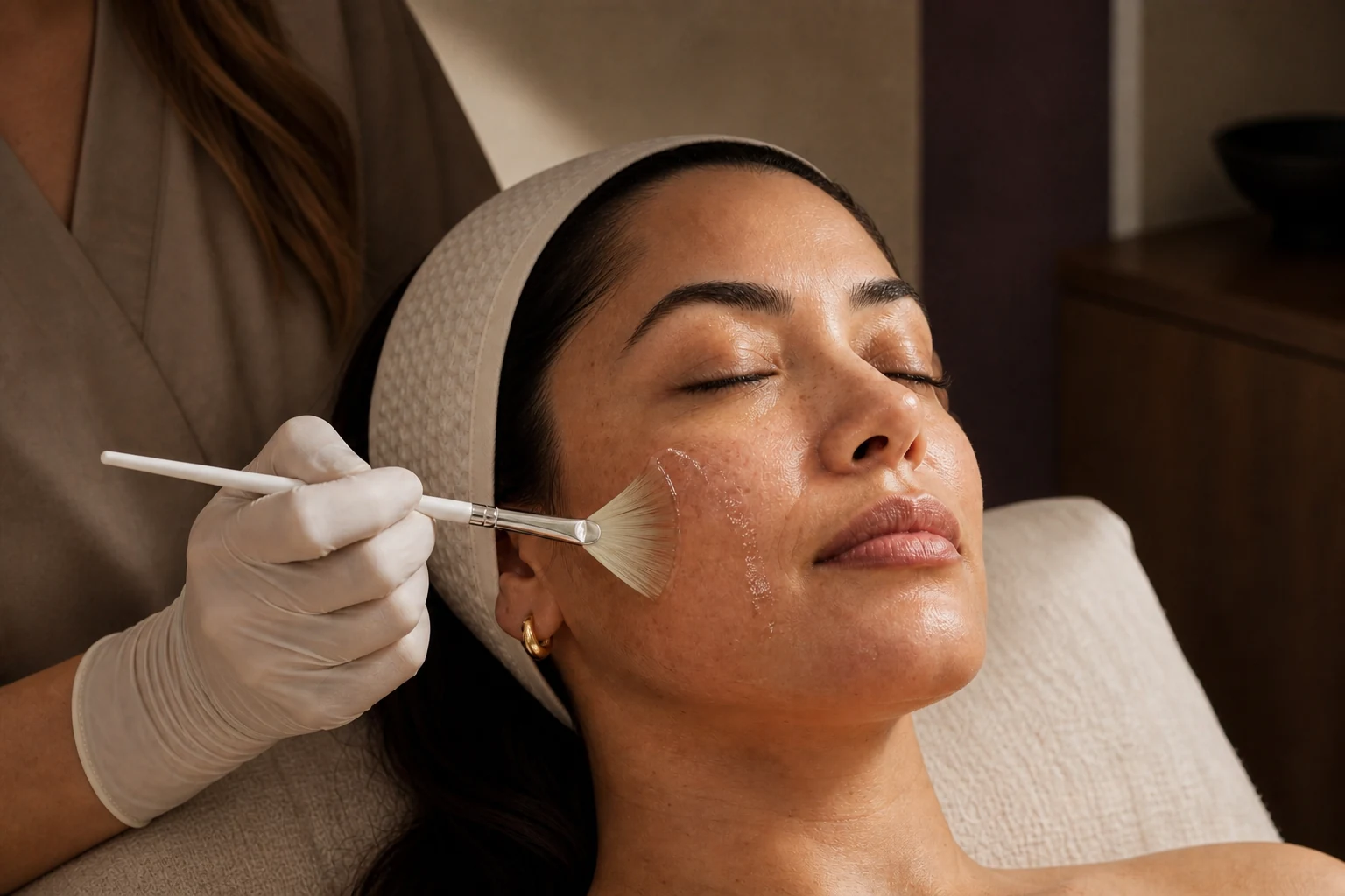 A skincare professional applying a chemical peel with a fan brush